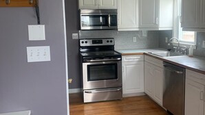 Una cocina moderna con armarios blancos, electrodomésticos de acero inoxidable y piso de madera.