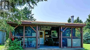 A small, rustic building with a porch, large windows, and a chimney. - Coastal Escape: Cottage Complex (Brackley Beach)