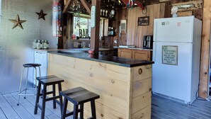 A rustic kitchen with wooden cabinets, a bar counter, and a refrigerator. - Coastal Escape: Cottage Complex (Brackley Beach)