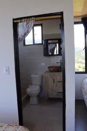 Une petite salle de bain compacte, équipée de toilettes, d’un lavabo et d’un miroir.