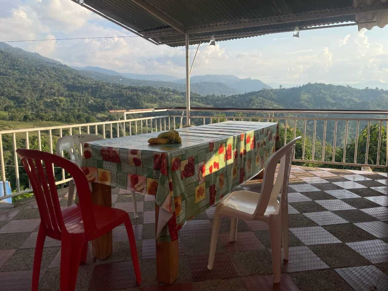 A table with a tablecloth, two chairs, and a banana on the table.