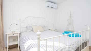 Une chambre à coucher comprenant un lit, des tables de chevet, un climatiseur fixé au mur et un élément décoratif mural.