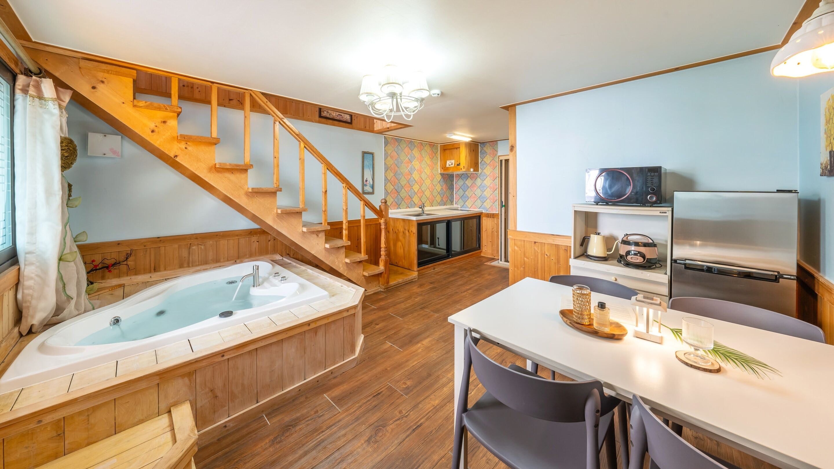 A cozy kitchen with a wooden staircase, a dining area, and a hot tub.