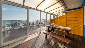A deck with a wooden table and chairs, a hammock, and a view of the ocean. - Yeongheungdo Blue Story Pension (Incheon)