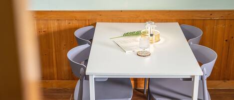 Un tavolo da pranzo con un menu, un bicchiere e una candela in una stanza con rivestimenti in legno e sedie grigie.