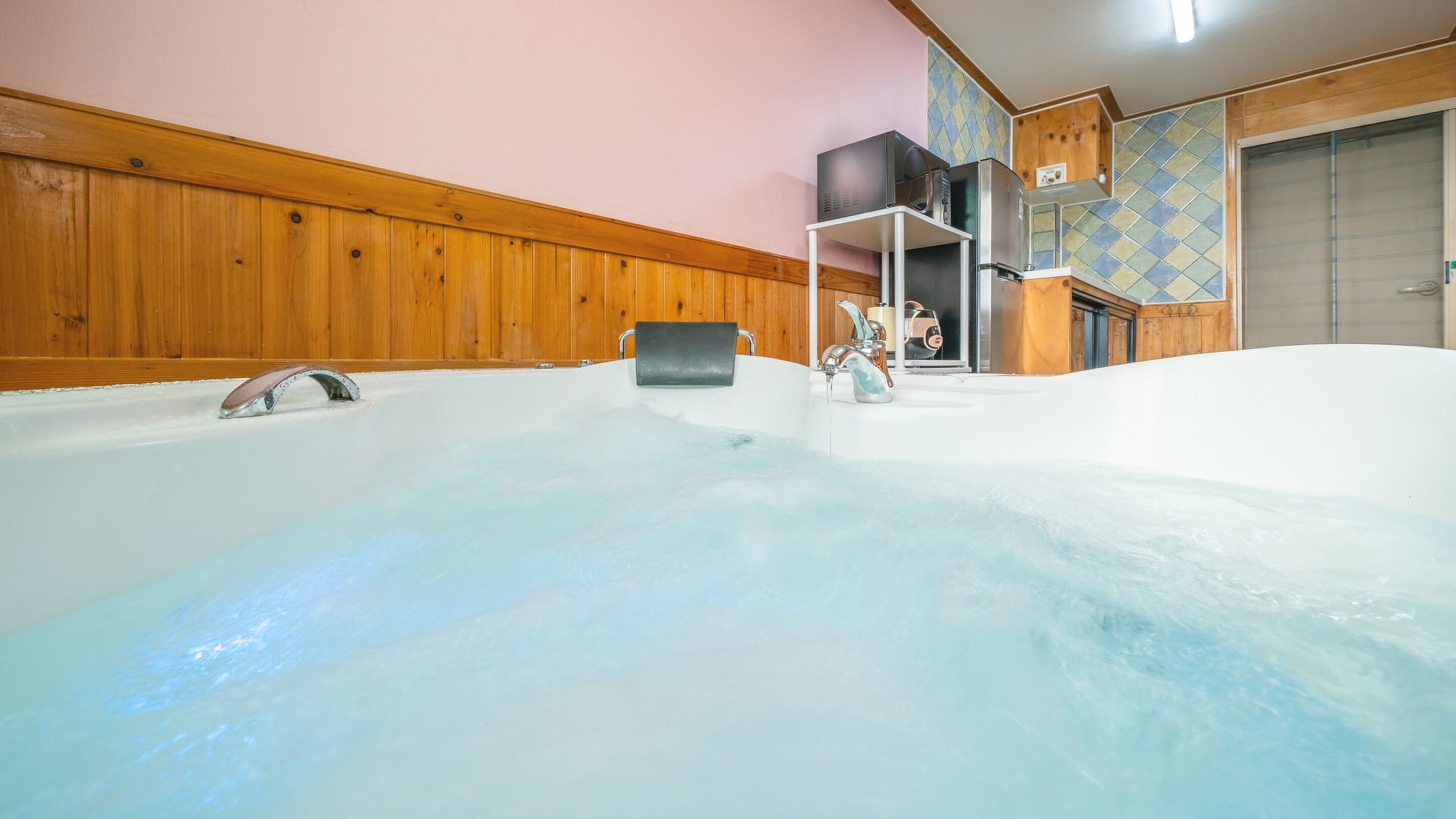 A large indoor hot tub with a wooden wall and tiled floor.