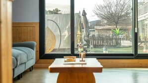 A modern living room with a large window, a wooden coffee table, and a grey sofa. - Yeongheungdo Blue Story Pension (Incheon)