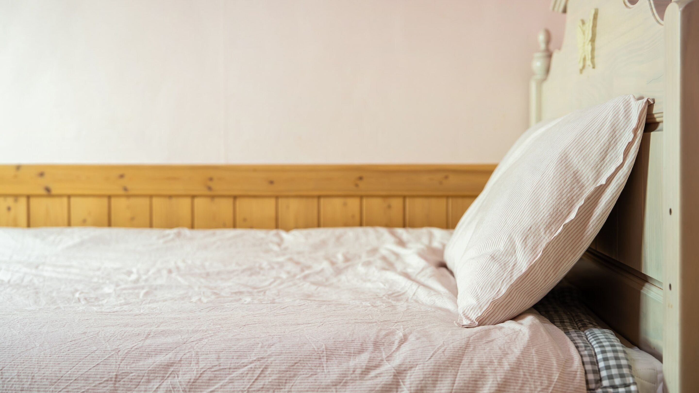 Una cama con cabecera de madera y una sola almohada.