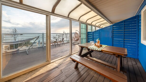 A wooden deck with a table and benches, overlooking a body of water. - Yeongheungdo Blue Story Pension (Incheon)