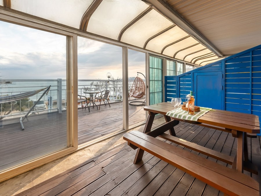 A wooden deck with a table and benches, overlooking a body of water.