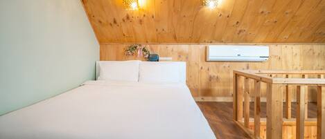 A bedroom with a wooden ceiling, a bed, a nightstand, and a small table.