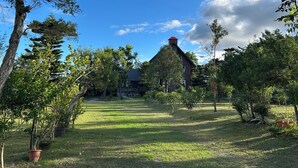 A house with a stone chimney, surrounded by a well-maintained lawn and various trees. - DF Life Lodge (Luye)