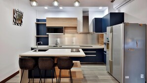 A modern kitchen with a central island, bar stools, a stainless steel refrigerator, and built-in appliances. - DF Life Lodge (Luye)