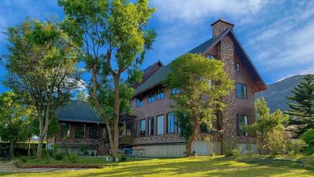 A large, two-story house with a stone chimney, surrounded by lush green trees and a well-maintained lawn. - DF Life Lodge (Luye)