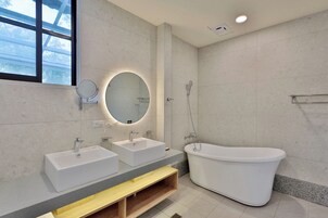 Un baño moderno con dos lavamanos, un espejo grande y una bañera independiente.