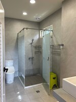 Un baño moderno con ducha envuelta en vidrio, inodoro, lavabo y bañera.