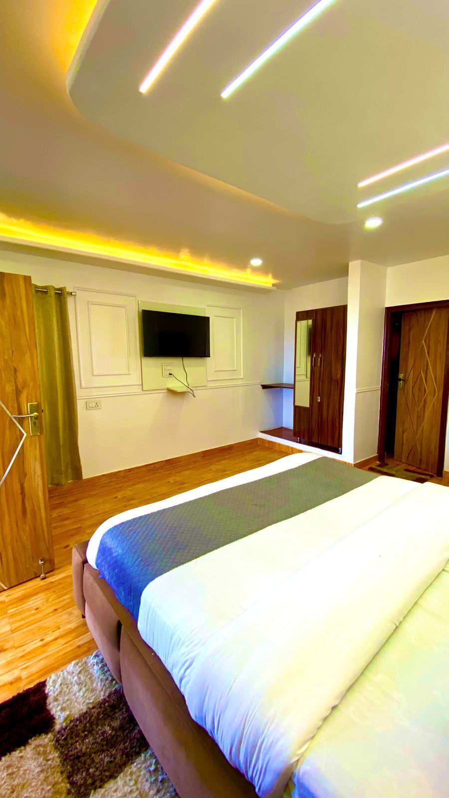 Un dormitorio con cama, suelo de madera, televisor de pantalla plana y armario.
