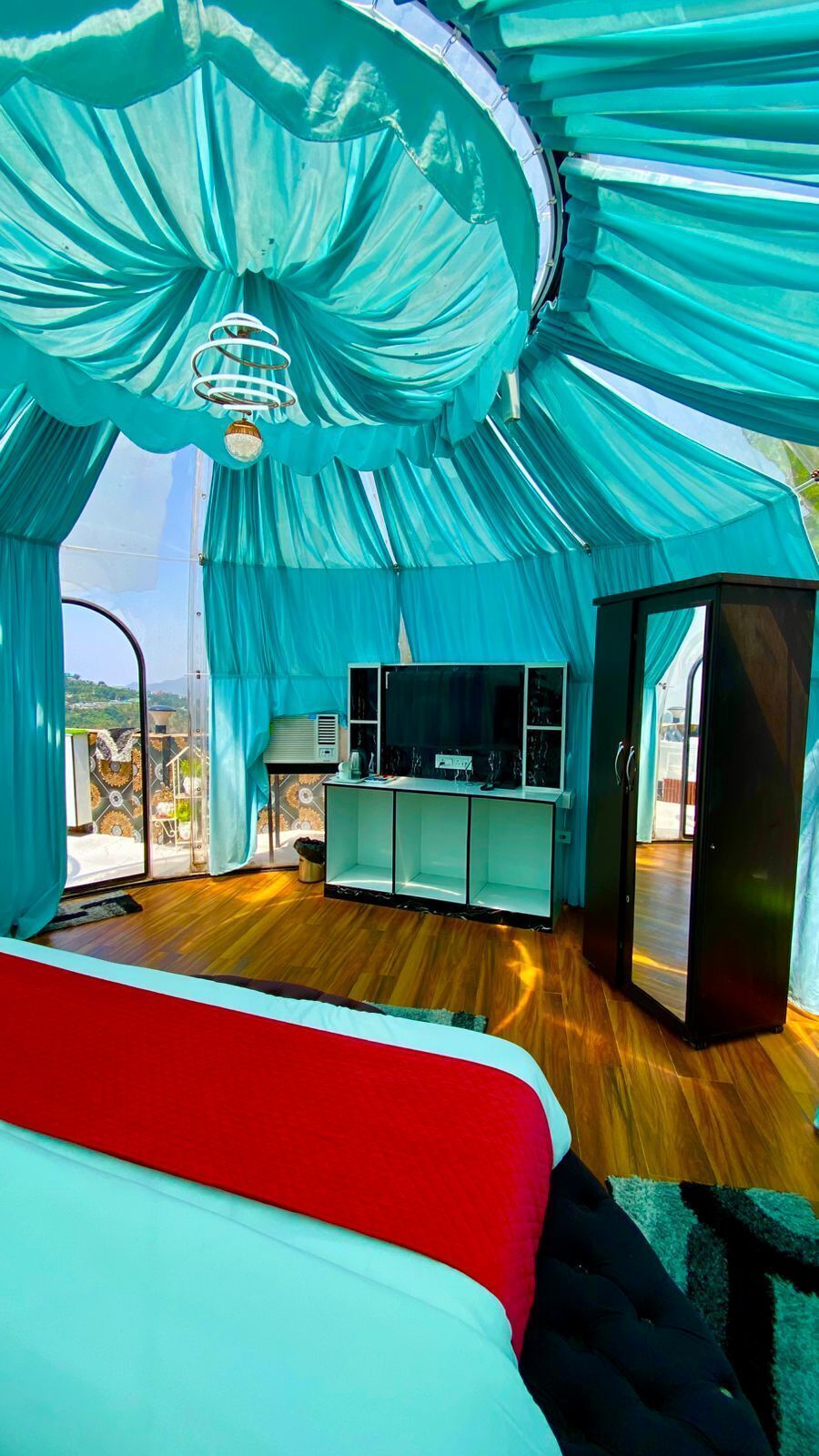 A room with a bed, a TV, and a large window.