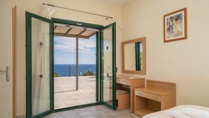 Une chambre d’hôtel avec un balcon, un lit, un bureau et un miroir.