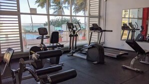 A gym with various exercise equipment, large windows, and a view of palm trees outside.