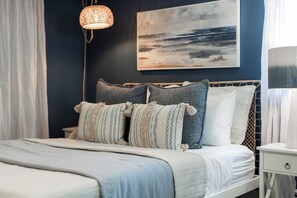 Et soveværelse med en seng, et natbord, en lampe, et vægmaleri og en pendel.