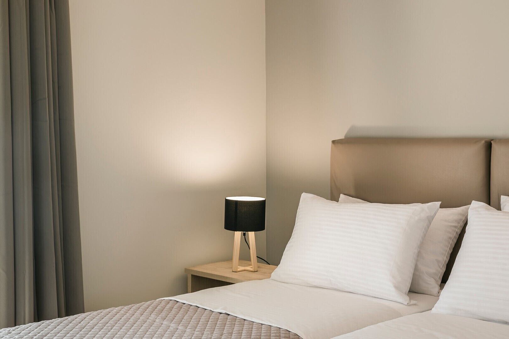 Une chambre d’hôtel avec un lit, une table de chevet avec une lampe et une fenêtre avec des rideaux.