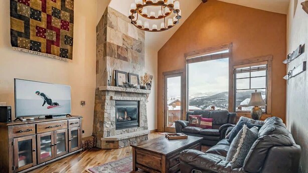 A cozy living room with a stone fireplace, leather sofa, and a television on a wooden cabinet. - 8 Mins to Trails | Near Shuttle (Winter Park)