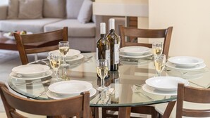 A dining table set for four with white plates, wine glasses, and bottles. - Villa Dinos with swimming pool (Kefallonia)