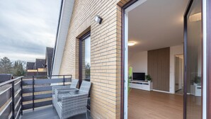 Een modern appartement met balkon, een flatscreen televisie en een houten vloer.