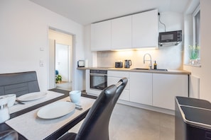 A modern kitchen with white cabinets, a microwave, an oven, and a sink. - Apartment 'Kroge' with Balcony and Wi-Fi (Uelzen)