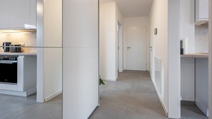 Een moderne keuken met witte kastjes, een ingebouwde oven en een aanrecht met een waterkoker.