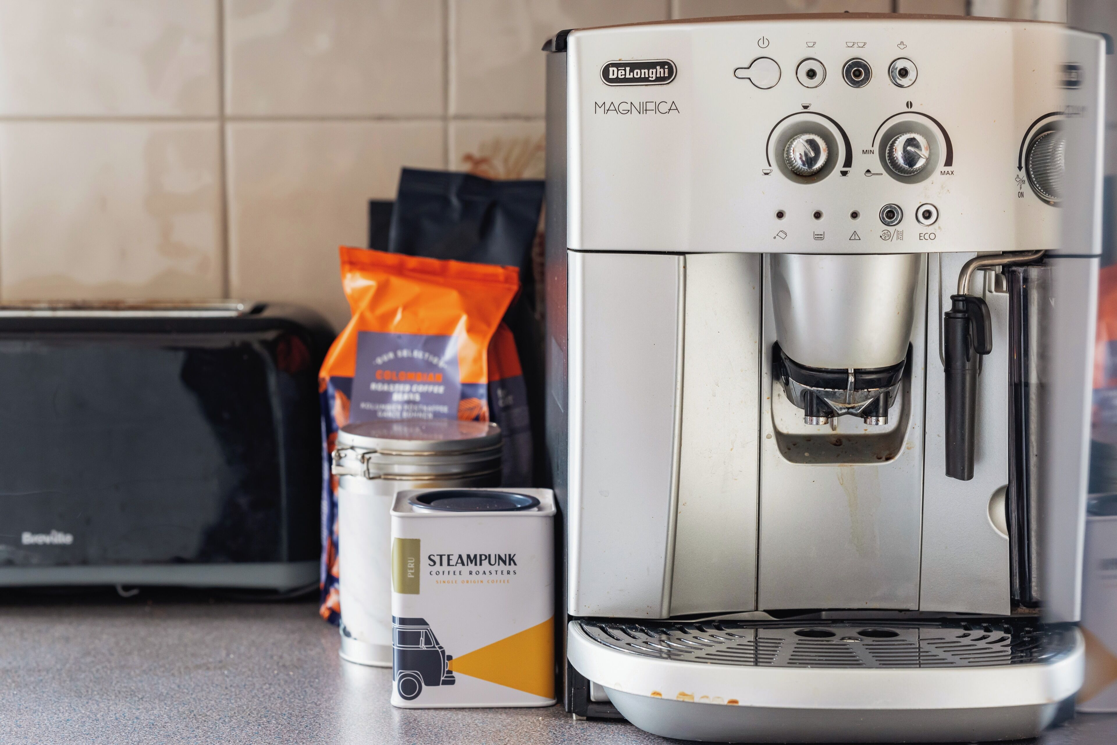 Una macchina da caffè De'Longhi MAGNIFICA con una cialda e una confezione di cialde.