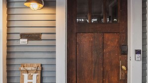 Een houten voordeur met een brievenbus en een welkomstbord.