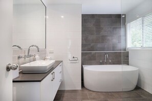 Ein modernes Badezimmer mit einer freistehenden Badewanne, einem Waschtisch und einem großen Spiegel.