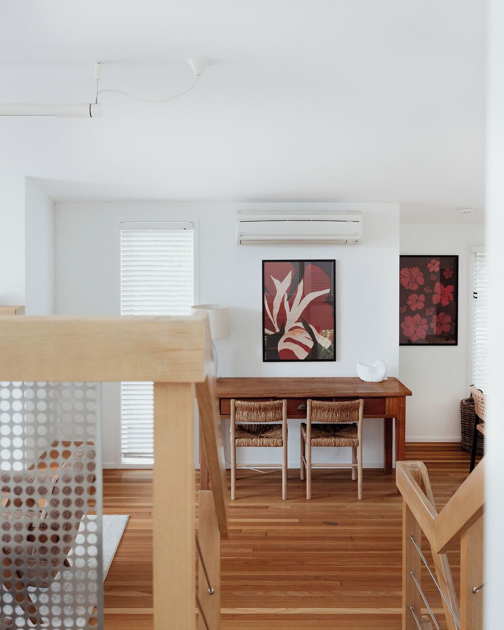 A modern dining area with a wooden table and chairs, white walls, and artwork.