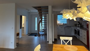 Moderni keittiö, jossa on valkoiset kaapit, puinen ruokapöytä ja ainutlaatuinen paperista valmistettu kattokruunu.