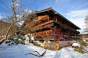 Eine Holzhütte mit Balkon, umgeben von Schnee und Bäumen.