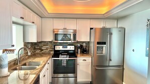 Una cocina moderna con electrodomésticos de acero inoxidable, encimera de granito y un diseño de techo original.