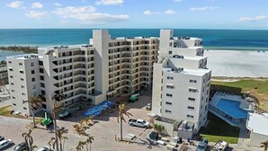 Un hotel de varios pisos con piscina, cerca de una playa bajo cielos despejados.