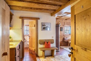 Interior de madera con un banco, una puerta y suelo de baldosas.