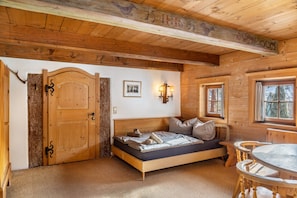 L’intérieur d’une cabane en bois, avec un lit, une table à manger et une porte en bois.