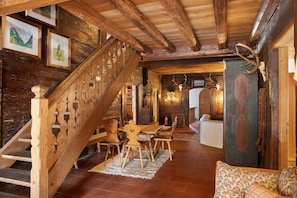 Un interior rústico con una escalera de madera, una zona de comedor y un sofá.