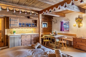 Una habitación rústica de madera con una cama, una mesa de madera, una silla, un escritorio pequeño y un armario.