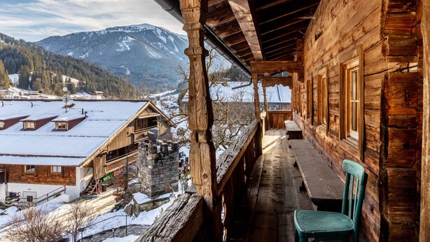 Une cabane en bois dotée d  ’un balcon donnant sur un village enneigé et des montagnes.