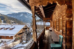A wooden cabin with a balcony overlooking a snowy village and mountains. - Apartment '09 Mühlfeldhof A4' with Mountain View, Shared Terrace and Wi-Fi (Kelchsau)