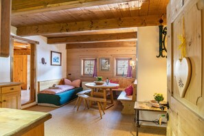 A wooden interior with a bed, a bench, a table, and a wall-mounted decoration.