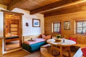 A cozy cabin with a bunk bed, a round dining table, and a bench.