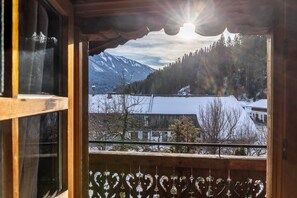A wooden balcony with a view of a snowy mountain landscape and a clear sky.