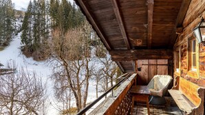 Eine Holzhütte mit Balkon mit Blick auf eine verschneite Landschaft.