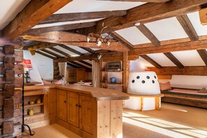 A rustic cabin interior with exposed wooden beams, a wooden bar, a cozy seating area, and a fireplace.
